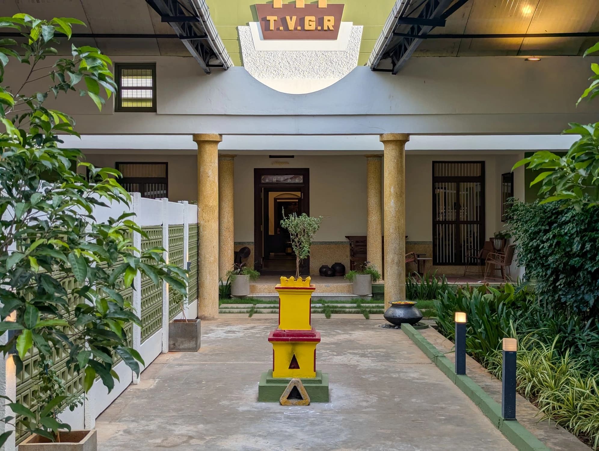 xl_Entrance Pathway- A verdant carpet of lush green plants lines the entrance pathway, leading to a traditional Tulsi Vrindavan (Tulsi plant) at its heart.